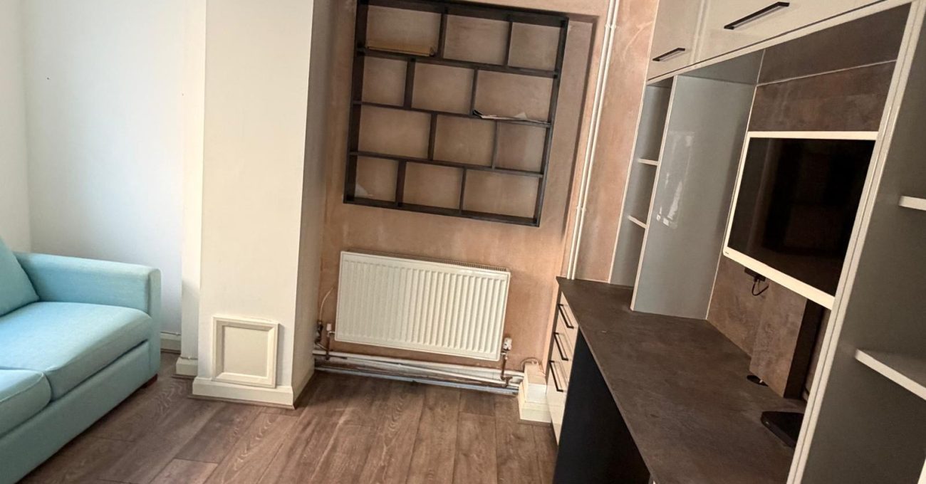 Bespoke fitted home office with grey cabinetry, black worktop, open shelving, wall-mounted TV and matching geometric wall storage.