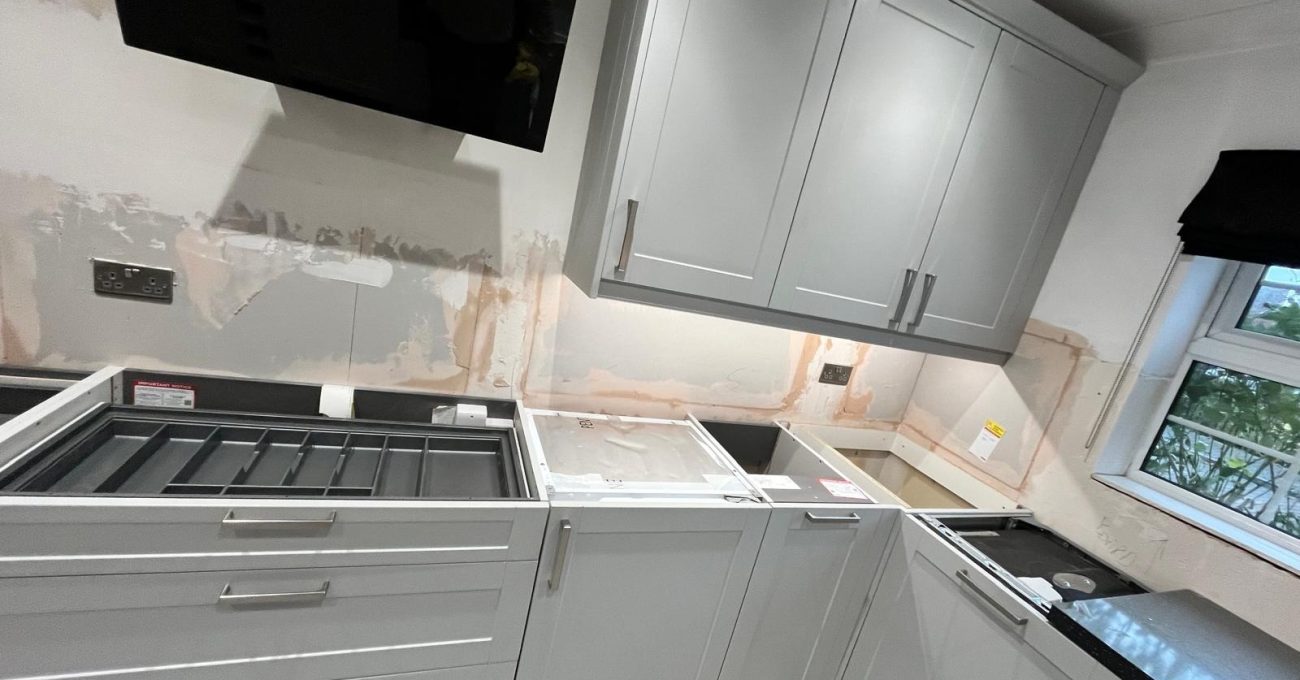 Newly fitted grey shaker kitchen cabinets and wall units in a Fleet kitchen with bare plaster walls awaiting tiling and worktop installation