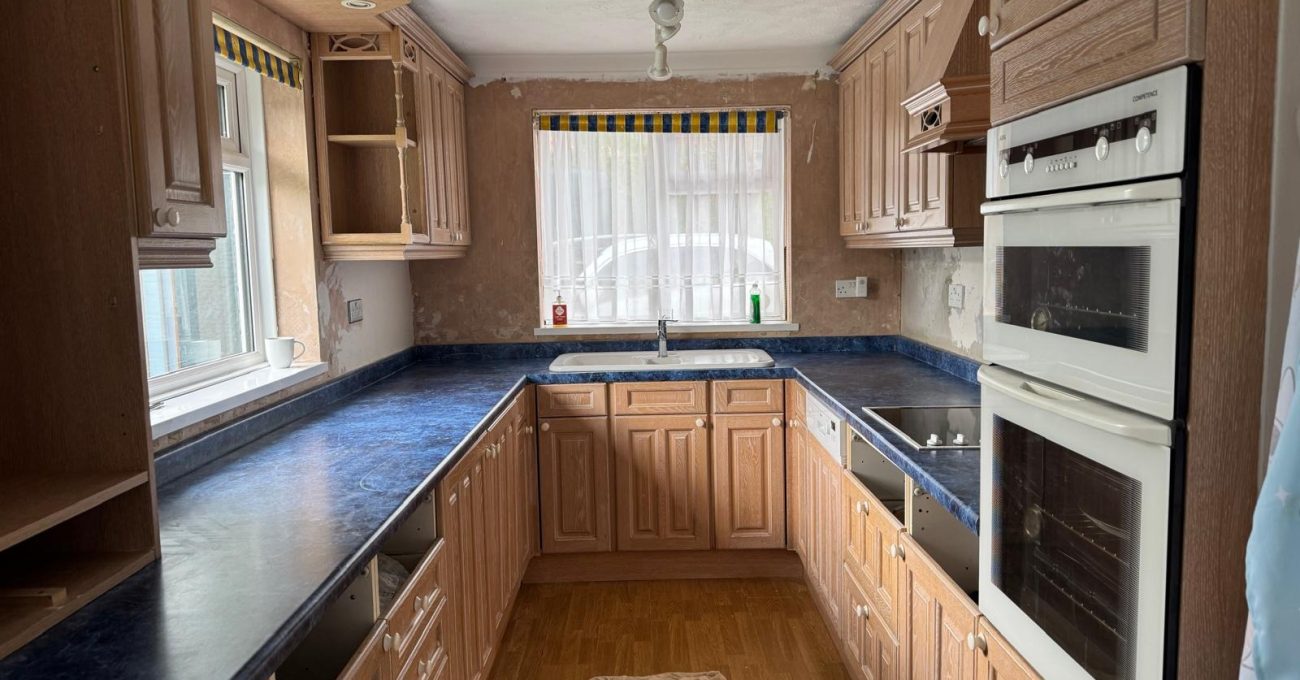 Dated kitchen in Blackwater, Surrey before its refresh, with worn dark worktops and old flooring
