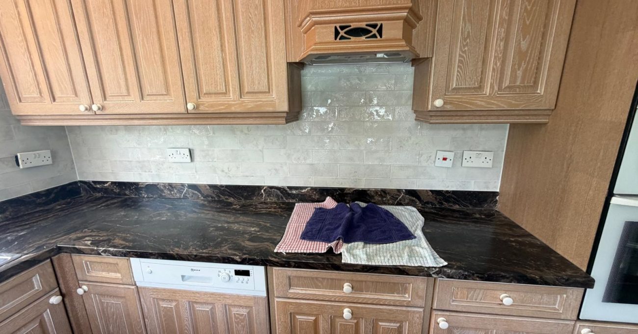Refreshed kitchen in Blackwater, Surrey with new pale wall tiles behind the hob and marbled worktops