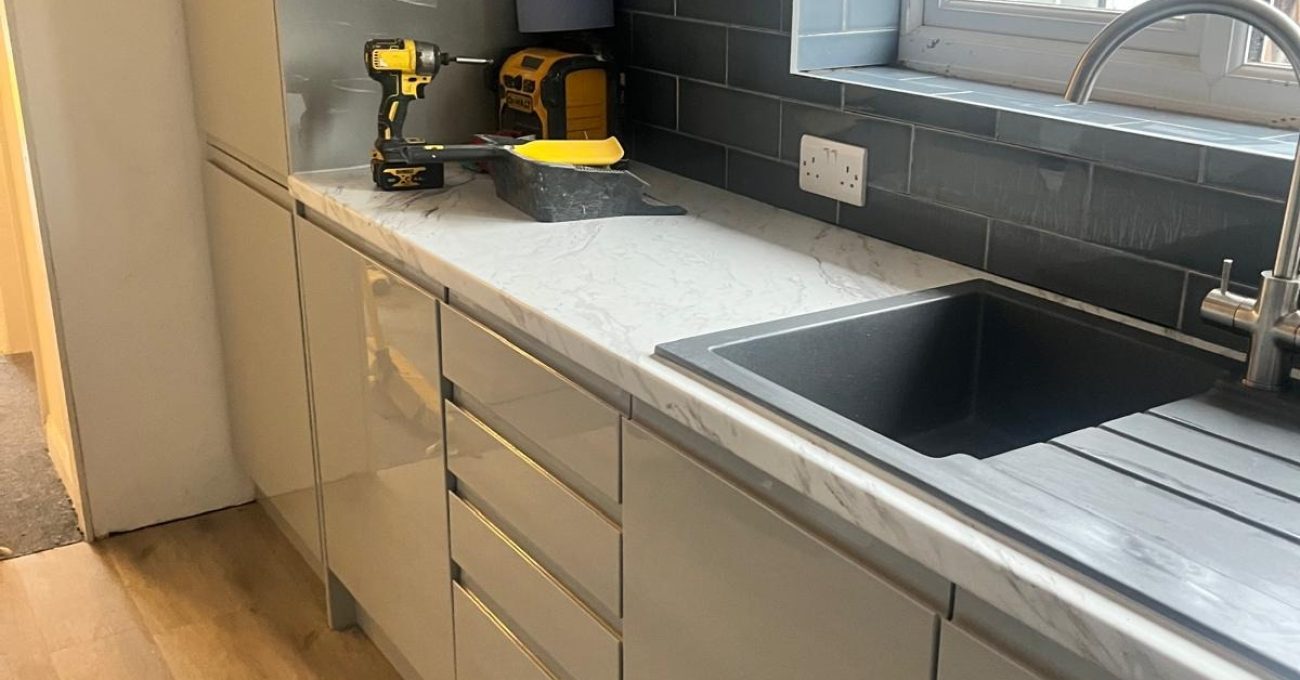 New sink and marble-effect laminate worktop in a Guildford, Surrey kitchen with teal metro tile splashback