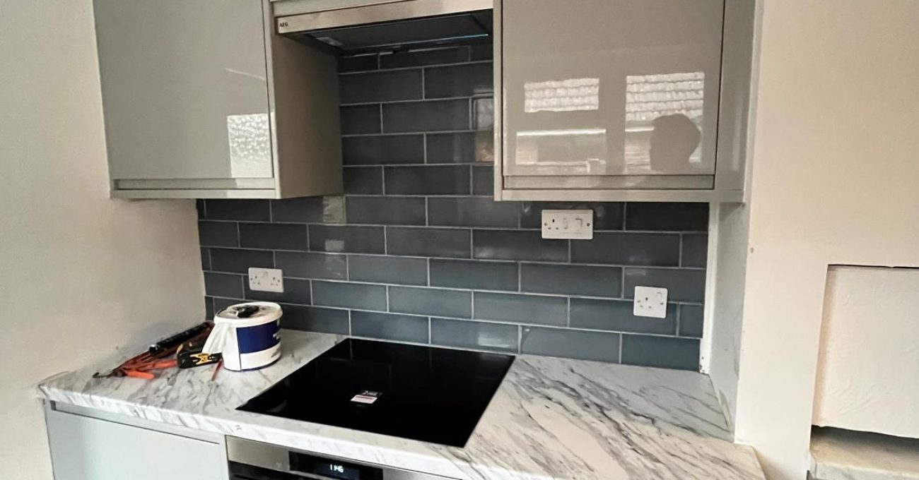 Completed Portofino kitchen in Guildford, Surrey with gloss painted units, teal metro splashback and integrated oven