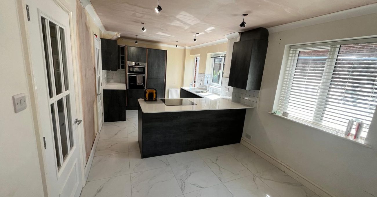 Completed open plan kitchen diner in Sandhurst, Berkshire with an island, anthracite units and marble-effect floor tiles